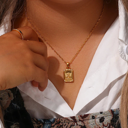A gold-plated stainless steel necklace with a square pendant featuring an angel figure, on a woman's neck