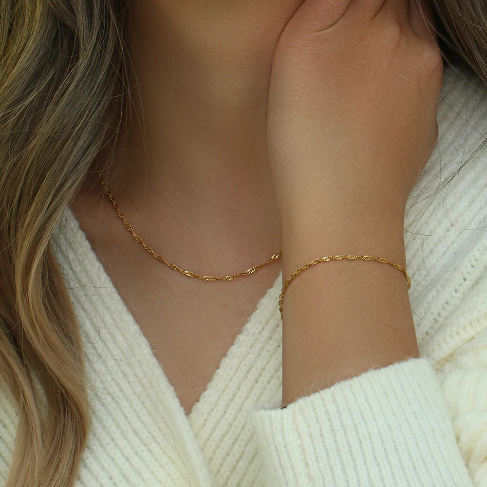A twisted chain necklace and bracelet, made from 18K gold plated stainless steel, on model.