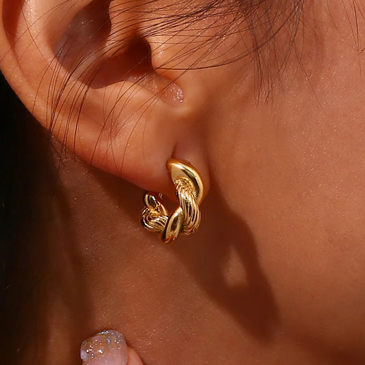 A pair of small, 18K gold plated twisted hoops earrings on a model