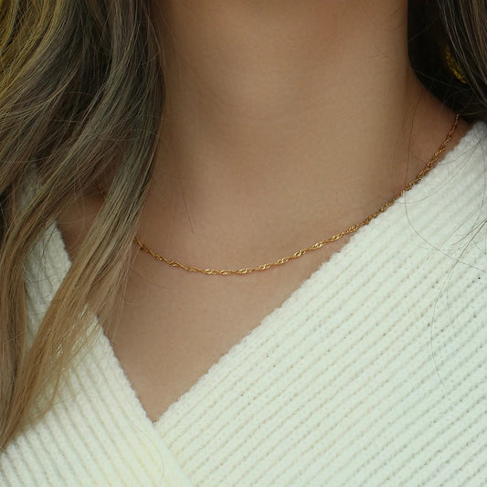 A delicate gold twisted chain necklace, displayed on model's neck
