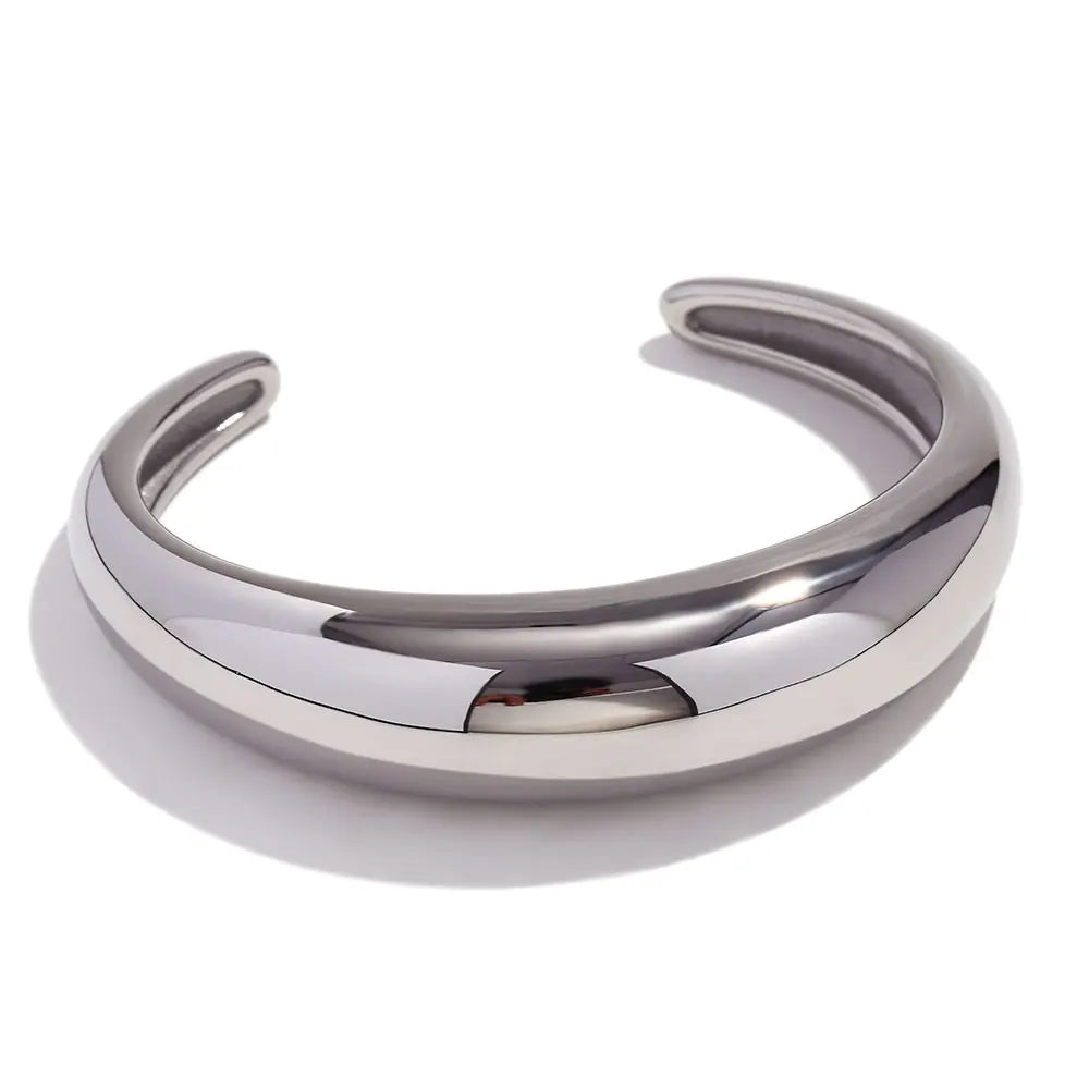 A sleek, stainless steel statement bangle bracelet with a polished finish, displayed against a white background