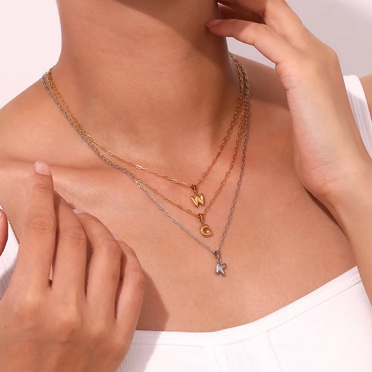 Necklace with letter pendants worn by a person on a light background