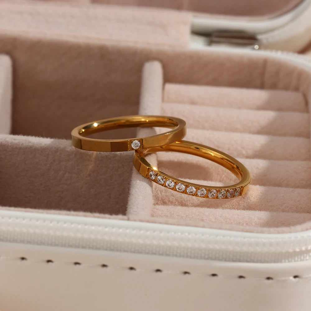 Gold ring with embedded diamonds on a soft pink cushion in a jewelry box.