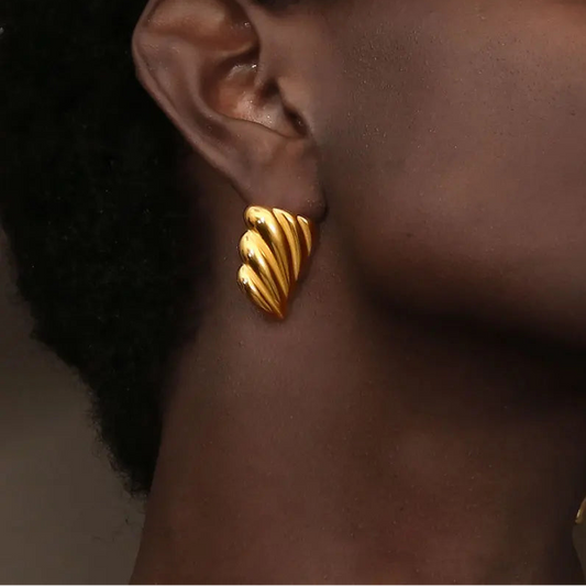 A pair of 18K gold plated stainless steel earrings with a sculpted, wave-like design on model