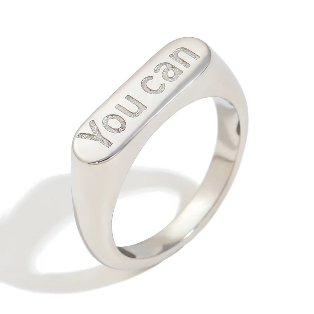 A stainless steel signet ring with the word 'you can' engraved on the top.