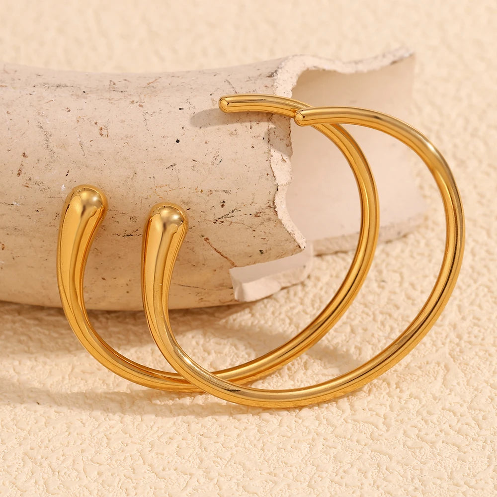 A gold steel bangle bracelet with a sleek, minimalist design