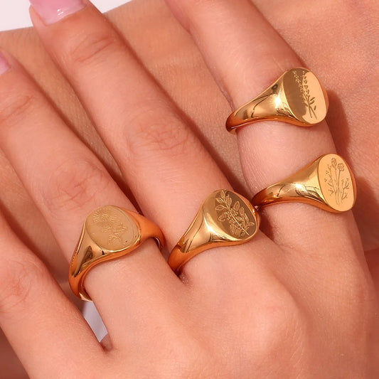 Gold flower signet rings on a models hand