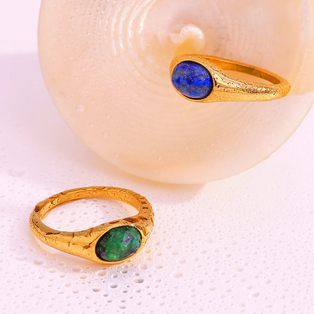 Golden rings with an oval blue or green gemstones set in the center, wet