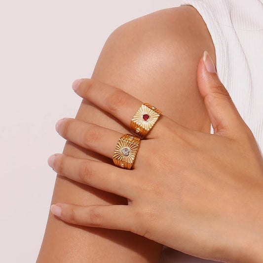 A gold stainless steel signet ring with a geometric design and crystal accents, on model's fingers