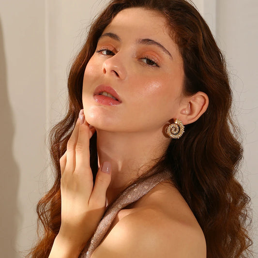 A pair of spiral design earrings adorned with pearls and zirconias, set in gold-plated metal.