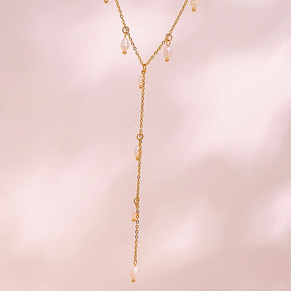 A gold lariat necklace with natural pearls, featuring a delicate design with multiple pearl drops along the chain.