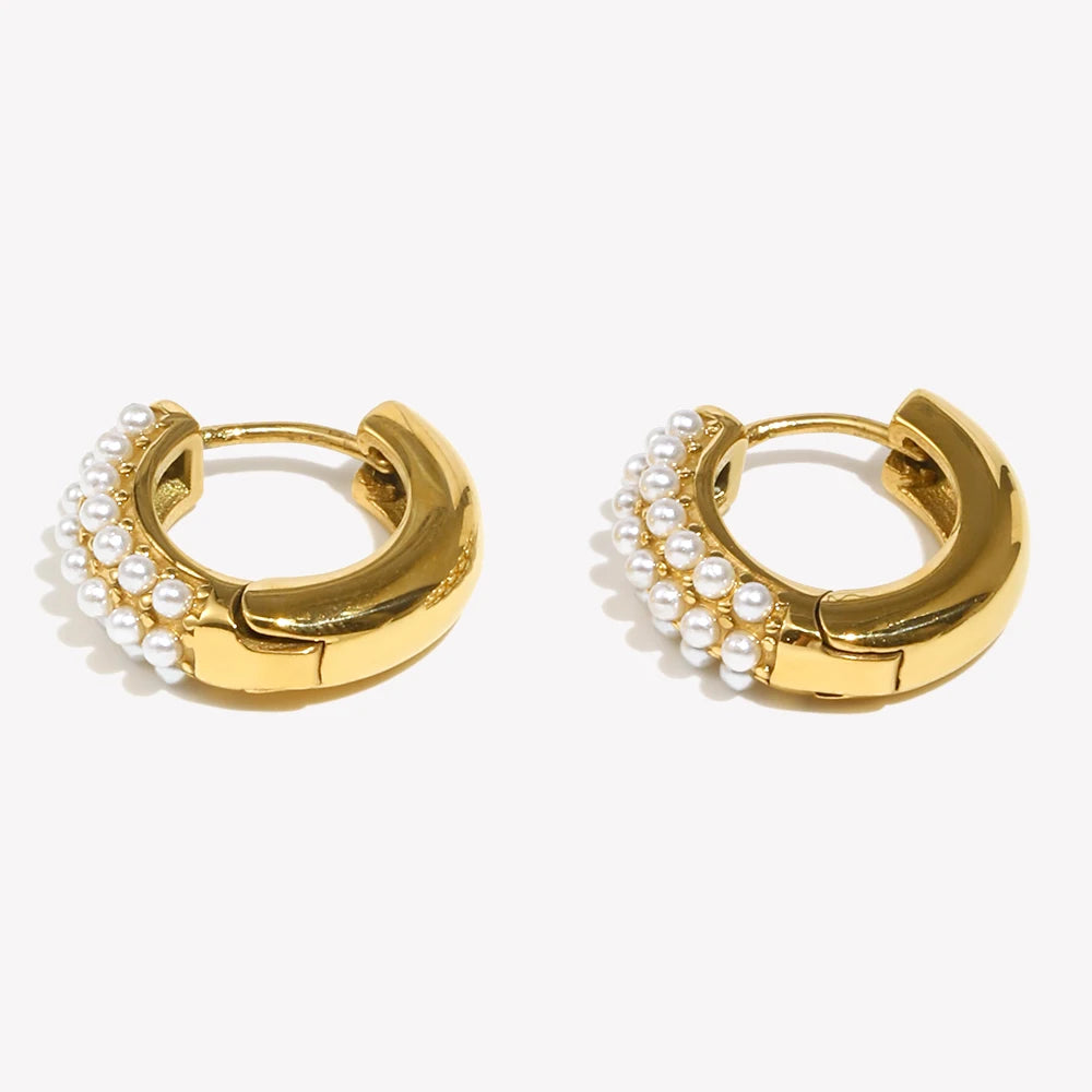 Gold hoop earrings with pearl accents laying flat on a white background