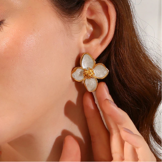 A pair of 18K gold coated floral earrings with white enamel petals on model