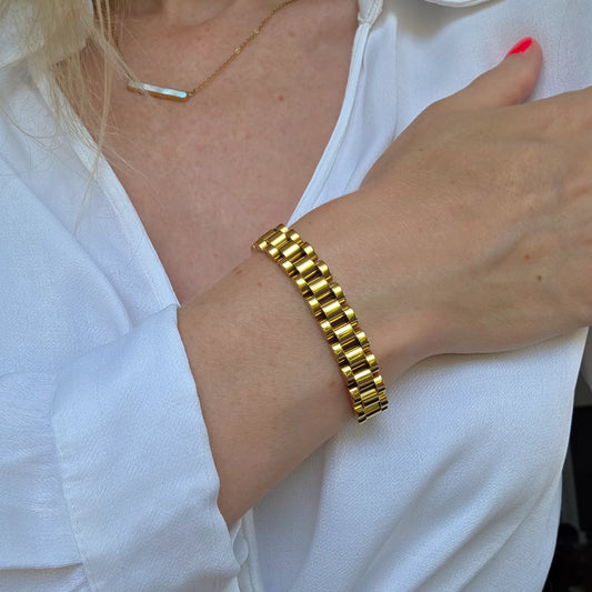 Gold stainless steel link bracelet on a person wearing a white shirt