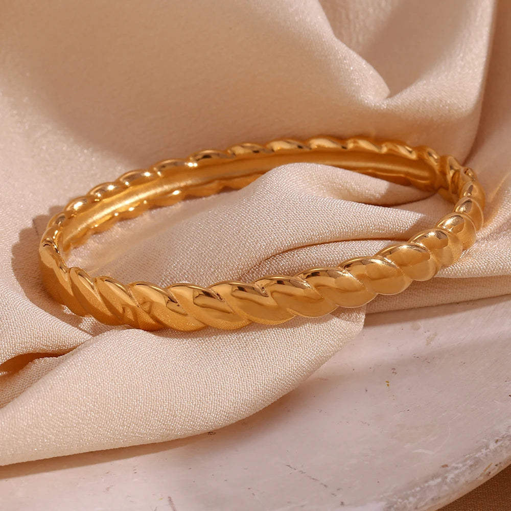 A gold twisted bangle bracelet with a shiny finish.