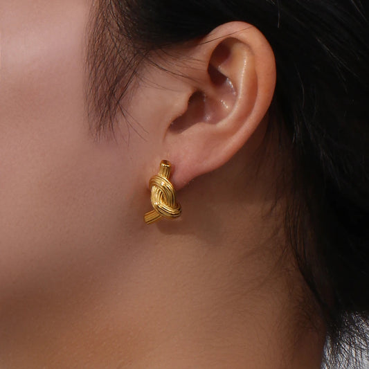 A pair of 18K gold plated stainless steel knot earrings with a textured surface on model