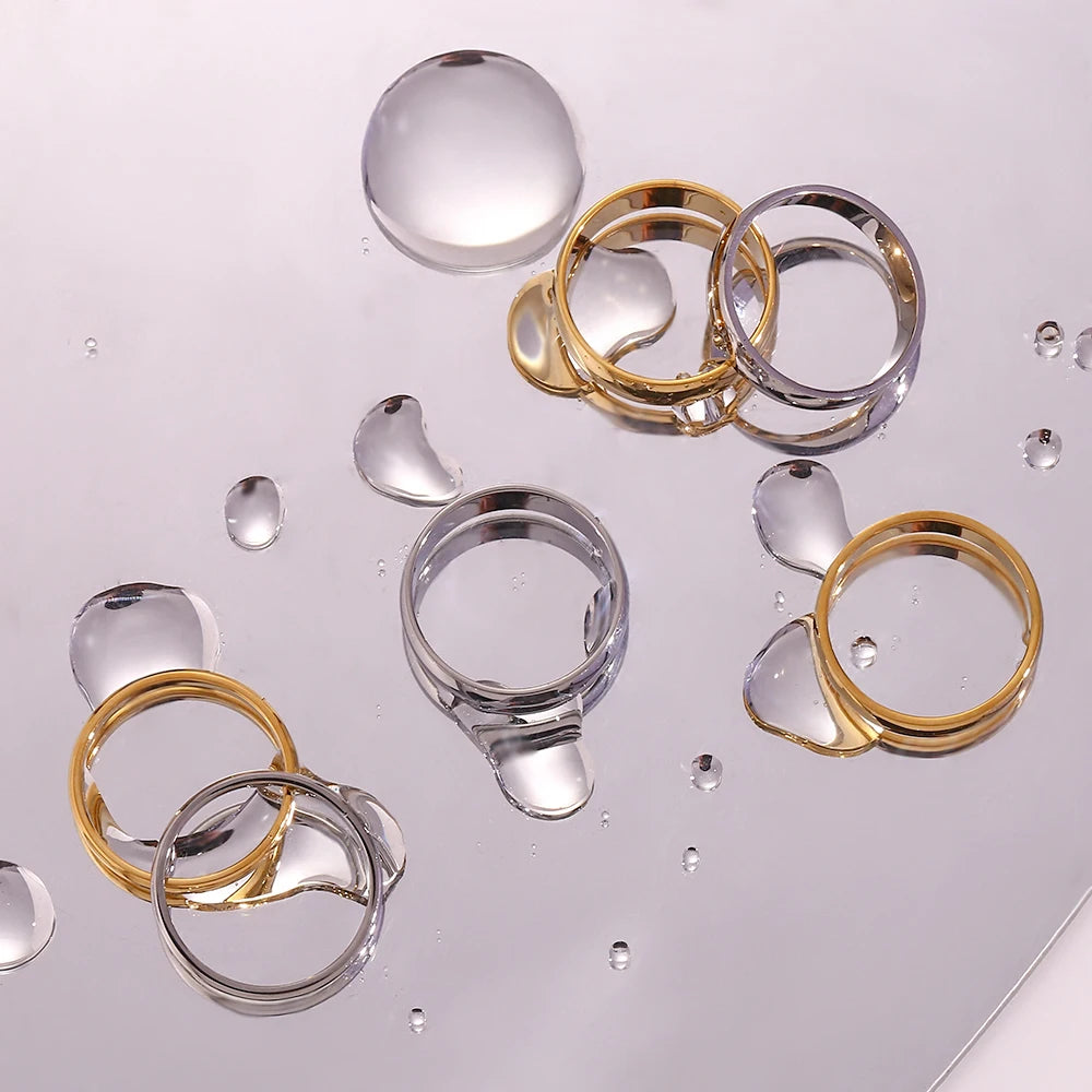 Gold and silver rings on a reflective surface with water droplets.