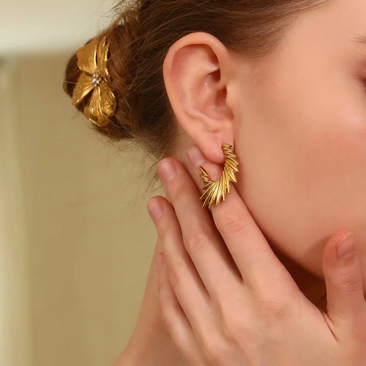 A pair of 18K gold plated stainless steel hoop earrings with a textured and spiky design on model