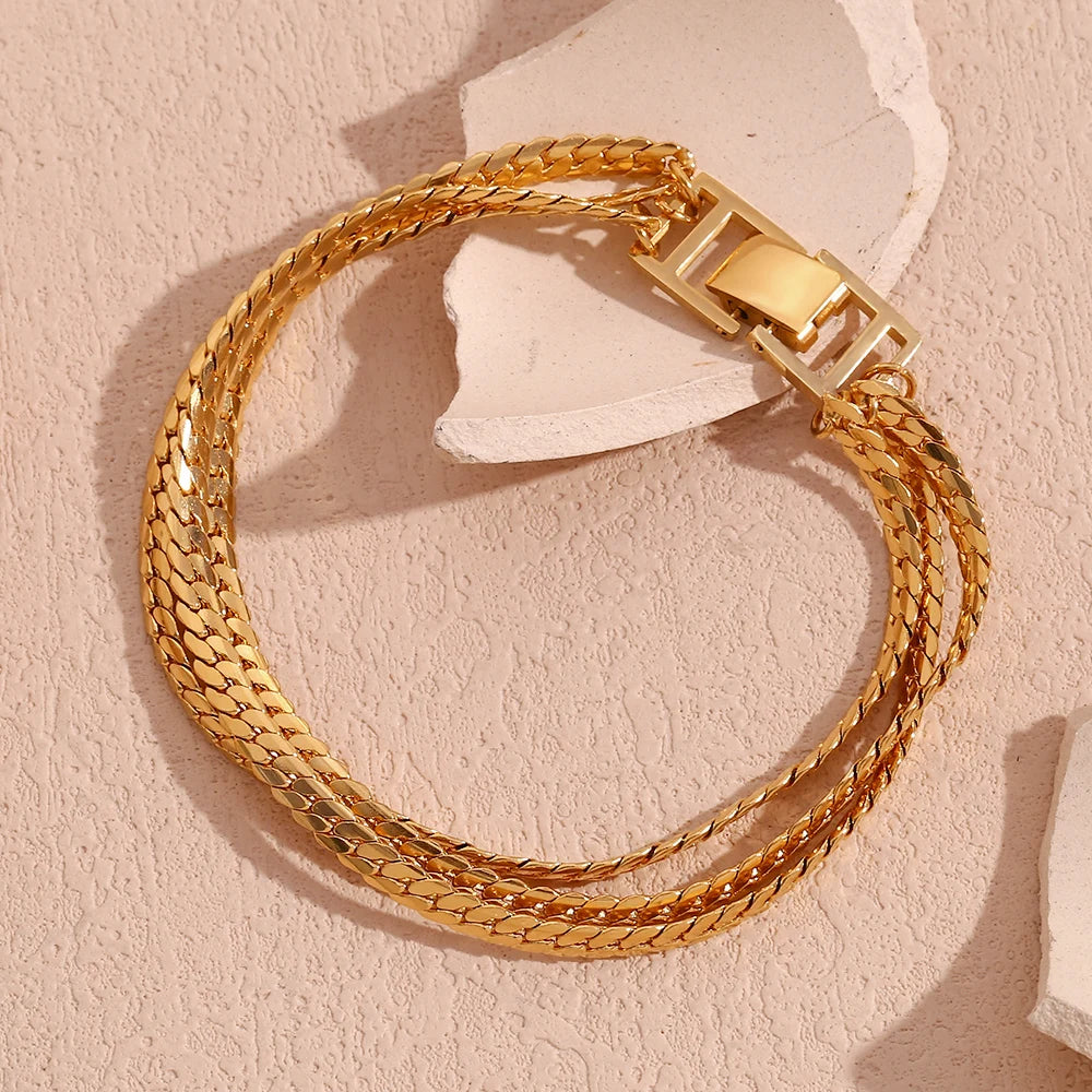 A gold stainless steel bracelet with a triple chain design, featuring a clasp closure.