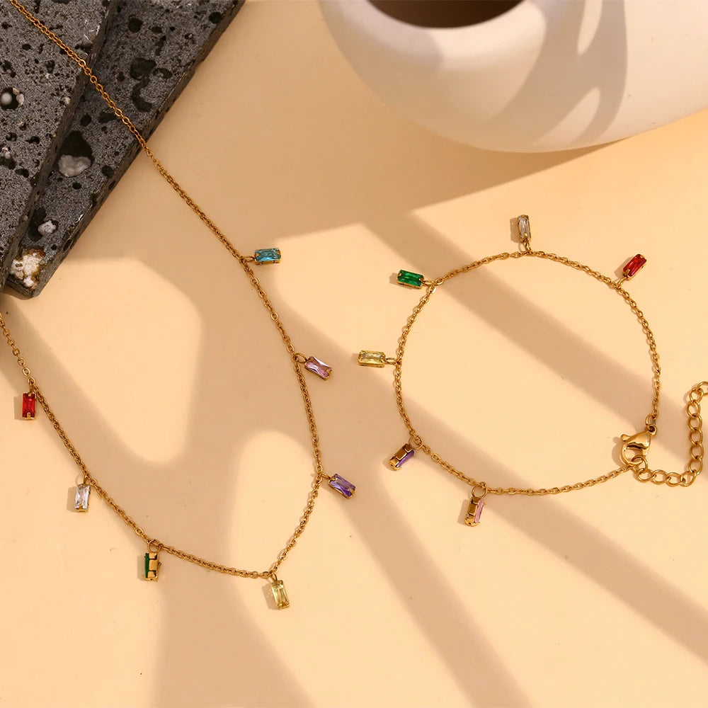 A golden necklace with multicolored zirconia charms attached to a gold chain,
