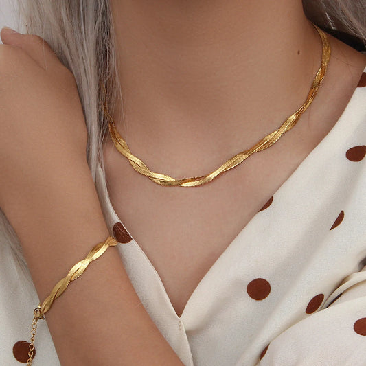 A gold twisted snake chain bracelet and matching necklace displayed on a model