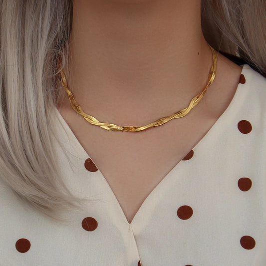 A gold twisted snake chain Necklace made from 18K gold plated stainless steel, displayed on a model's neck.