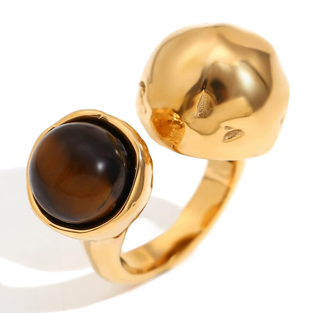 An 18K gold platted ring with a round tiger's eye stone on a hammer textured, asymmetrical band.