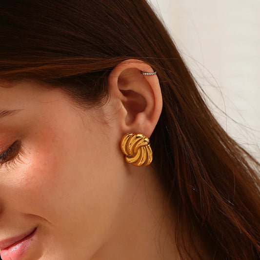 A pair of timeless gold earrings with a twisted design, crafted from 18K gold plated stainless steel on model