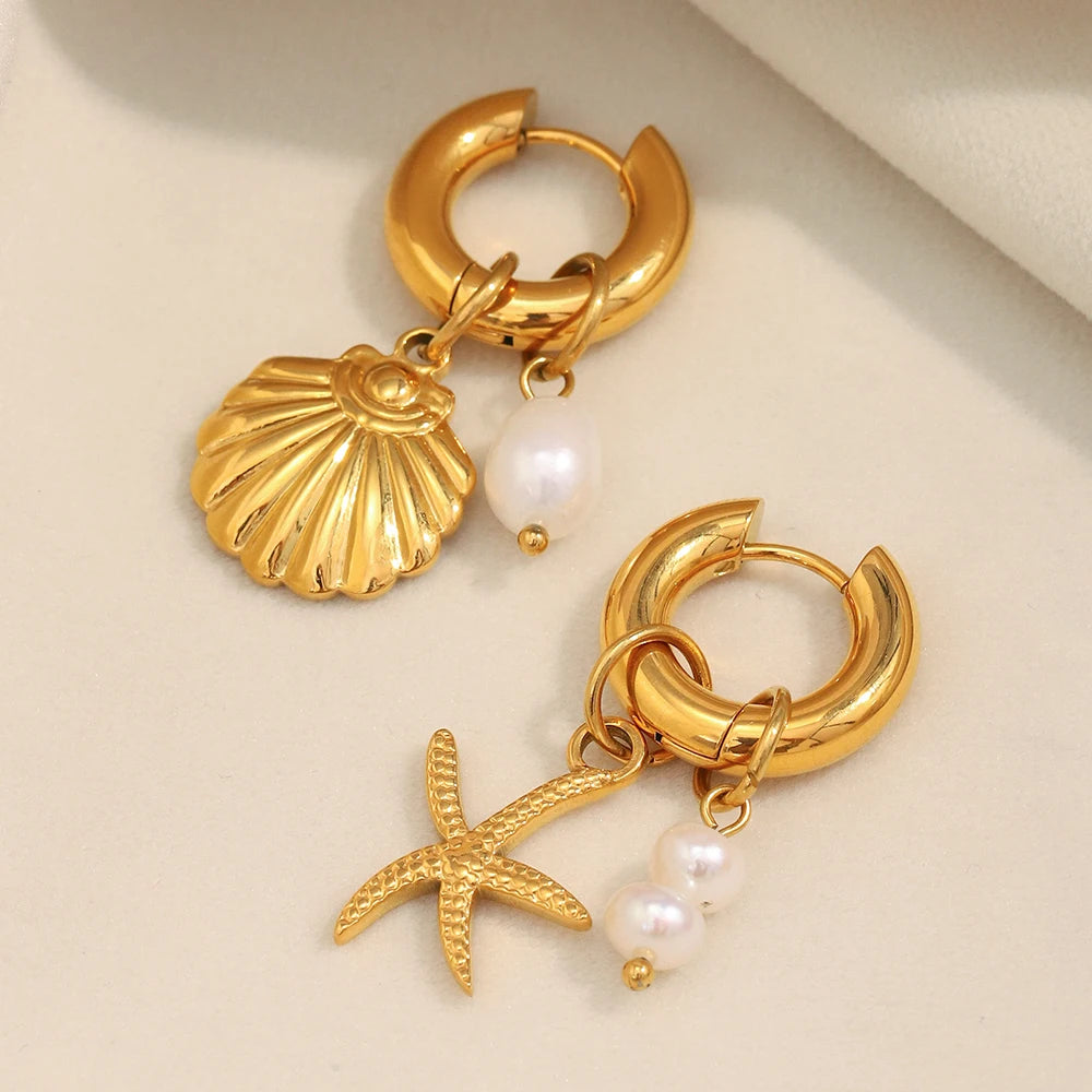 Gold hoop earrings with shell and starfish charms on a beige background