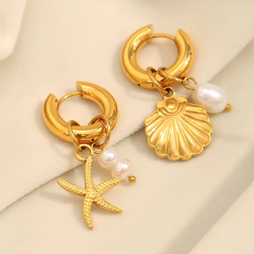 Gold hoop earrings with shell and starfish charms on a beige background