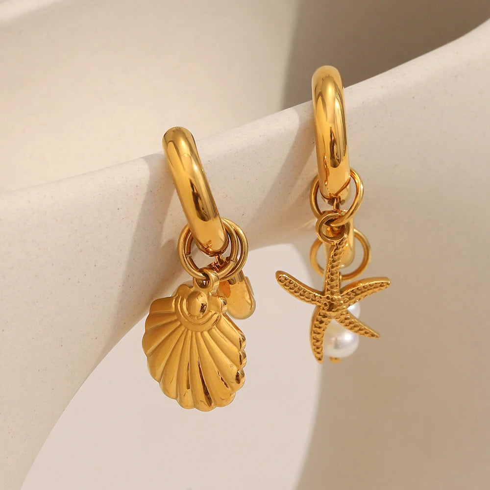 Gold hoop earrings with shell and starfish charms on a beige background