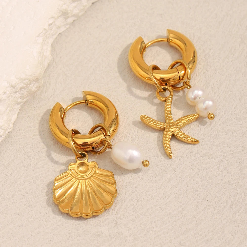 Gold hoop earrings with starfish and shell charms on a beige background