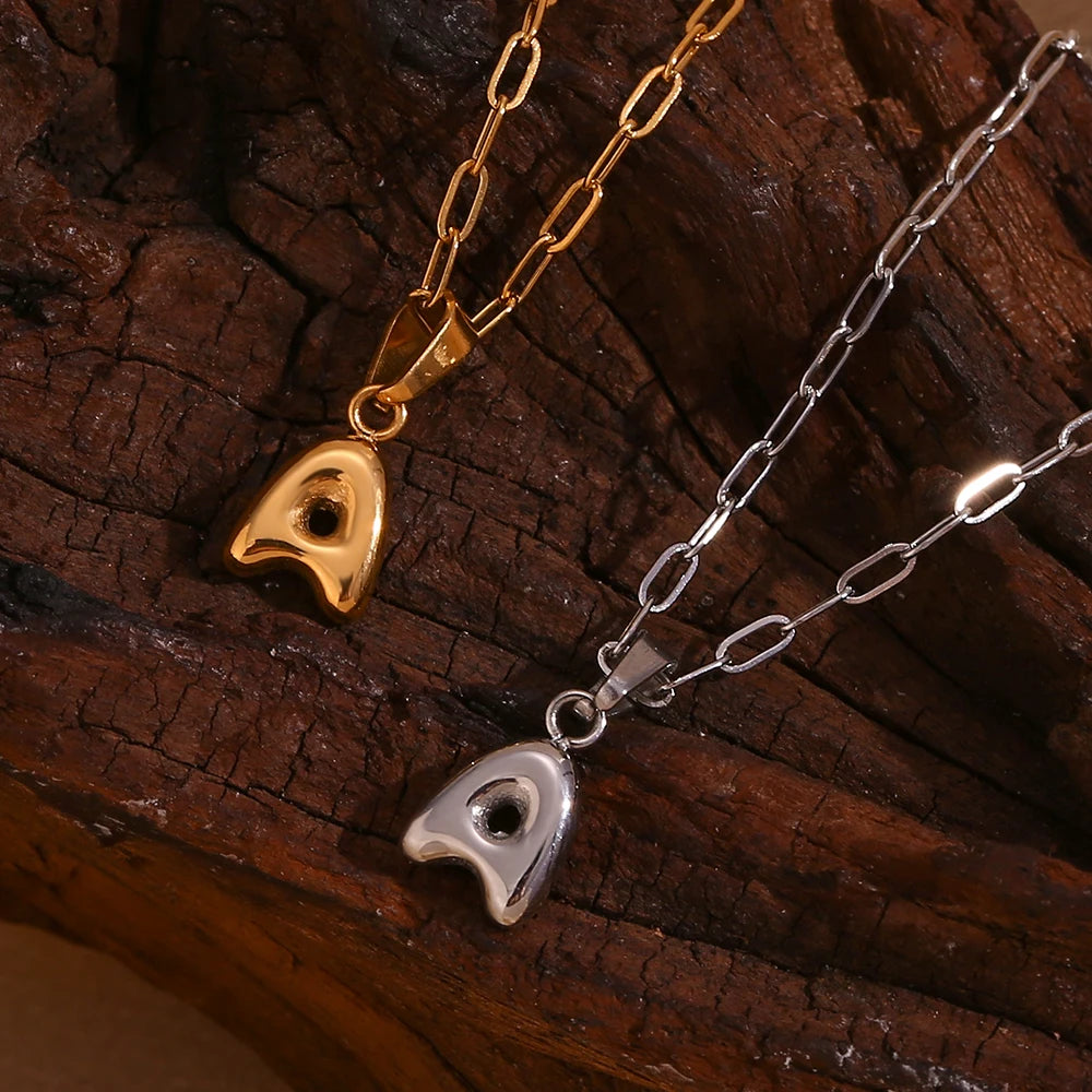 Two necklaces with letter 'A' pendants on a wooden surface