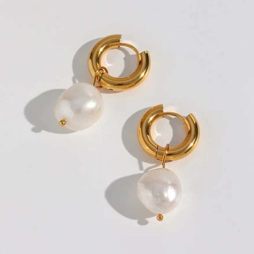 Gold hoop earrings with pearl drops on a light gray background