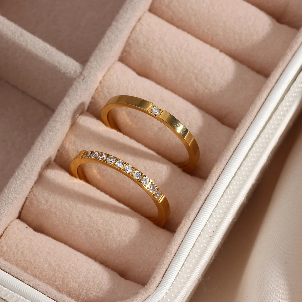 Two gold rings with diamond accents in a pink jewelry box.