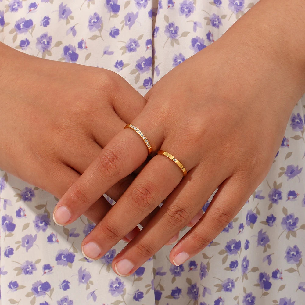 Close-up of two hands wearing gold rings on a floral dress background