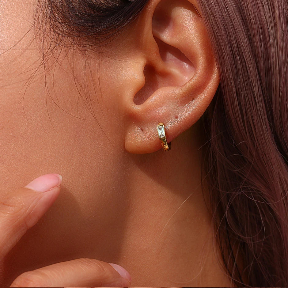Close-up of someone wearing a gold hoop earring with a blurred background