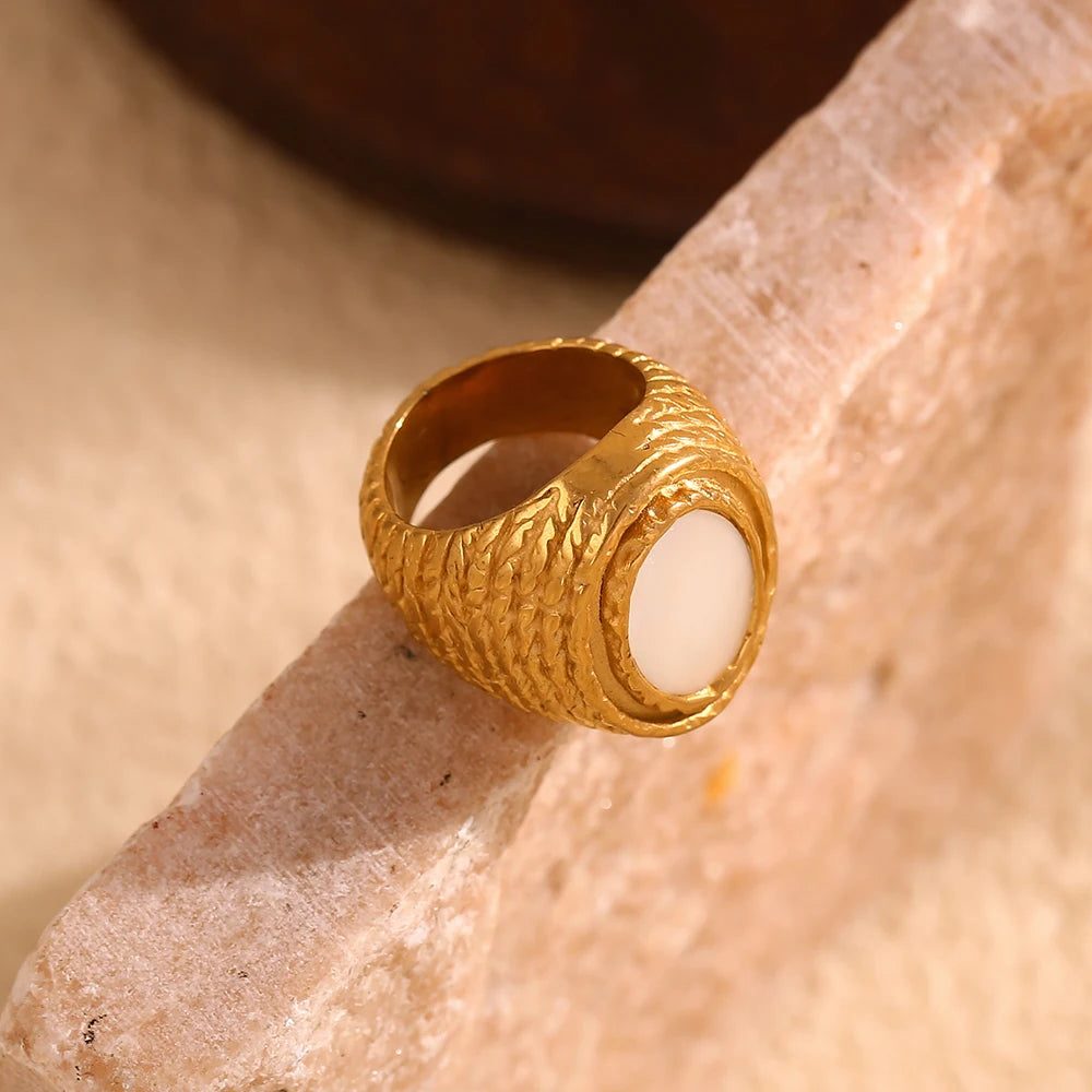 A chunky gold stainless steel ring with a natural white shell inset, 
