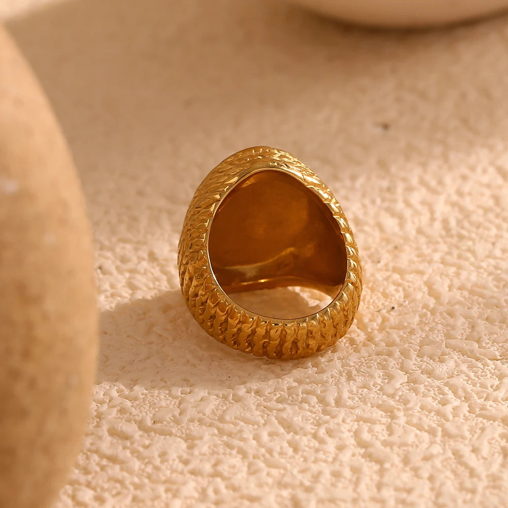 A chunky gold stainless steel ring with a natural white shell inset, 