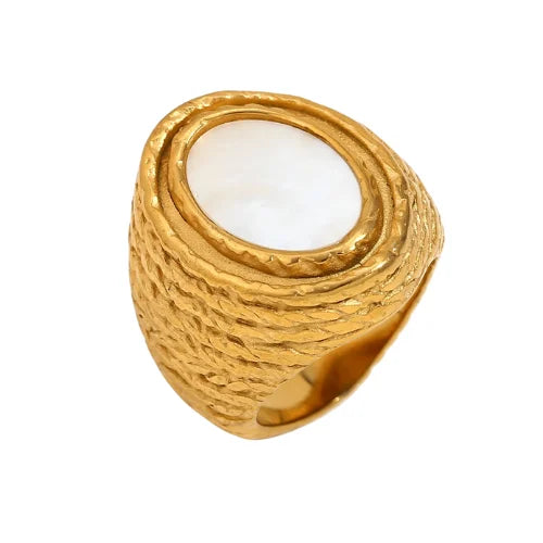Gold chunky steel ring with a central white shell on a white background