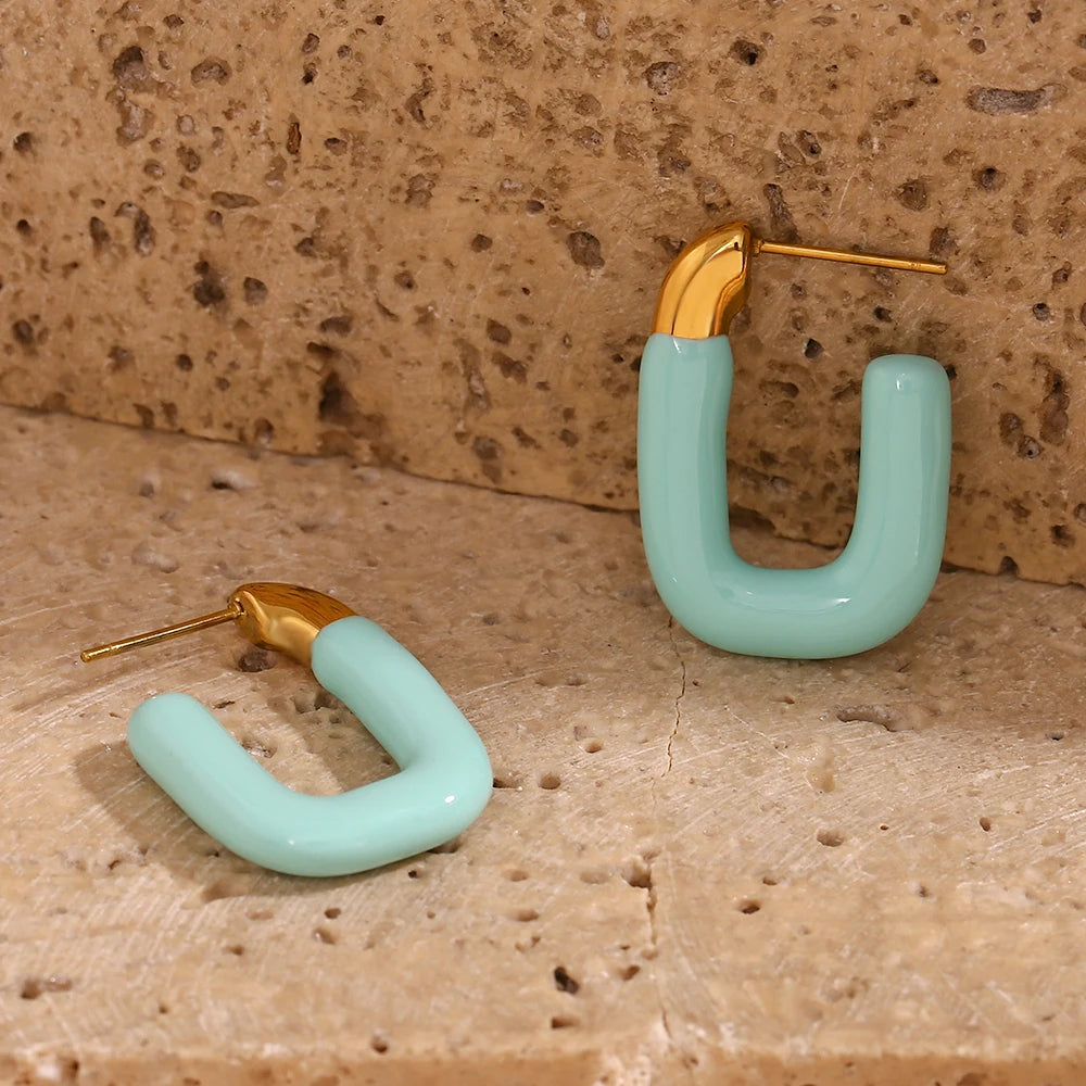 A pair of gold-colored hoop earrings with a pastel blue coating.