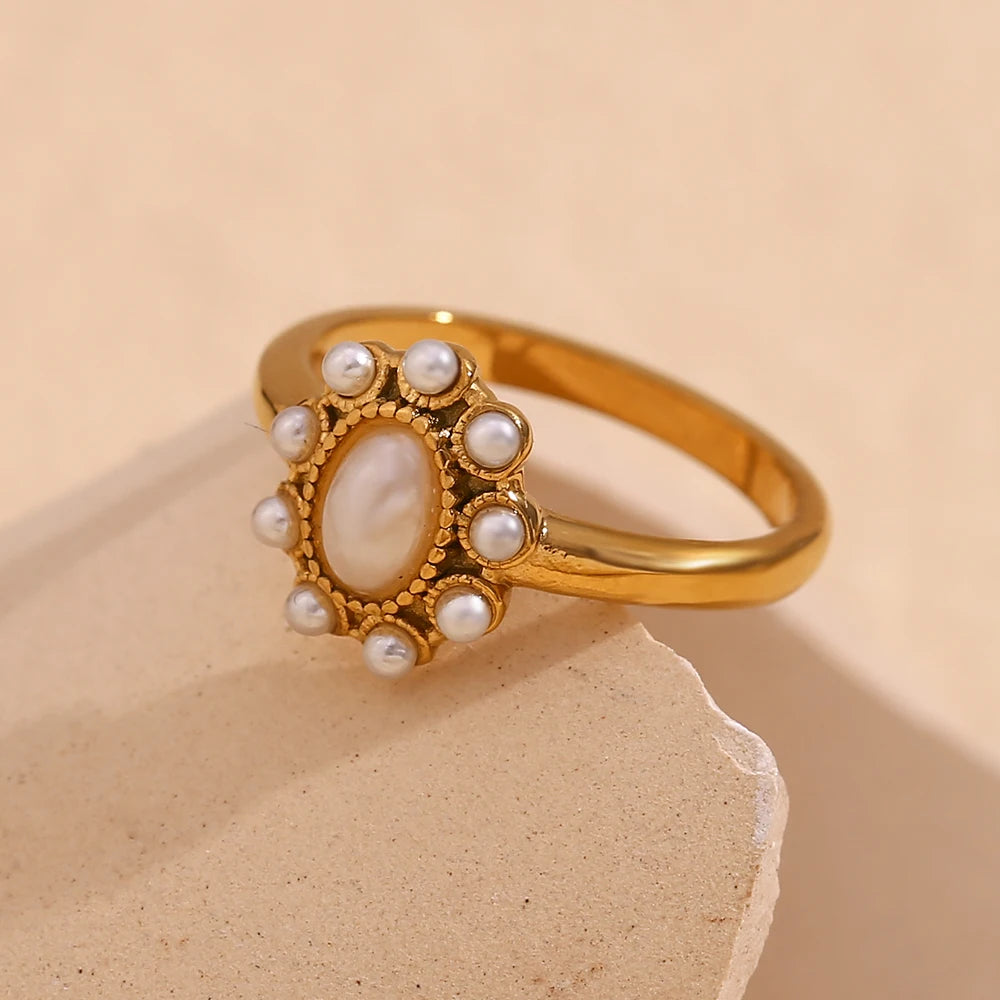 Gold ring with pearls on a beige stone surface