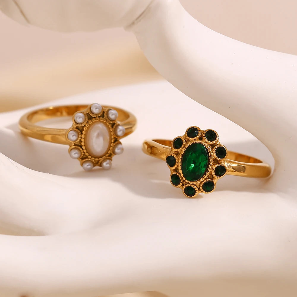 Two gold rings with oval gemstones on a white surface