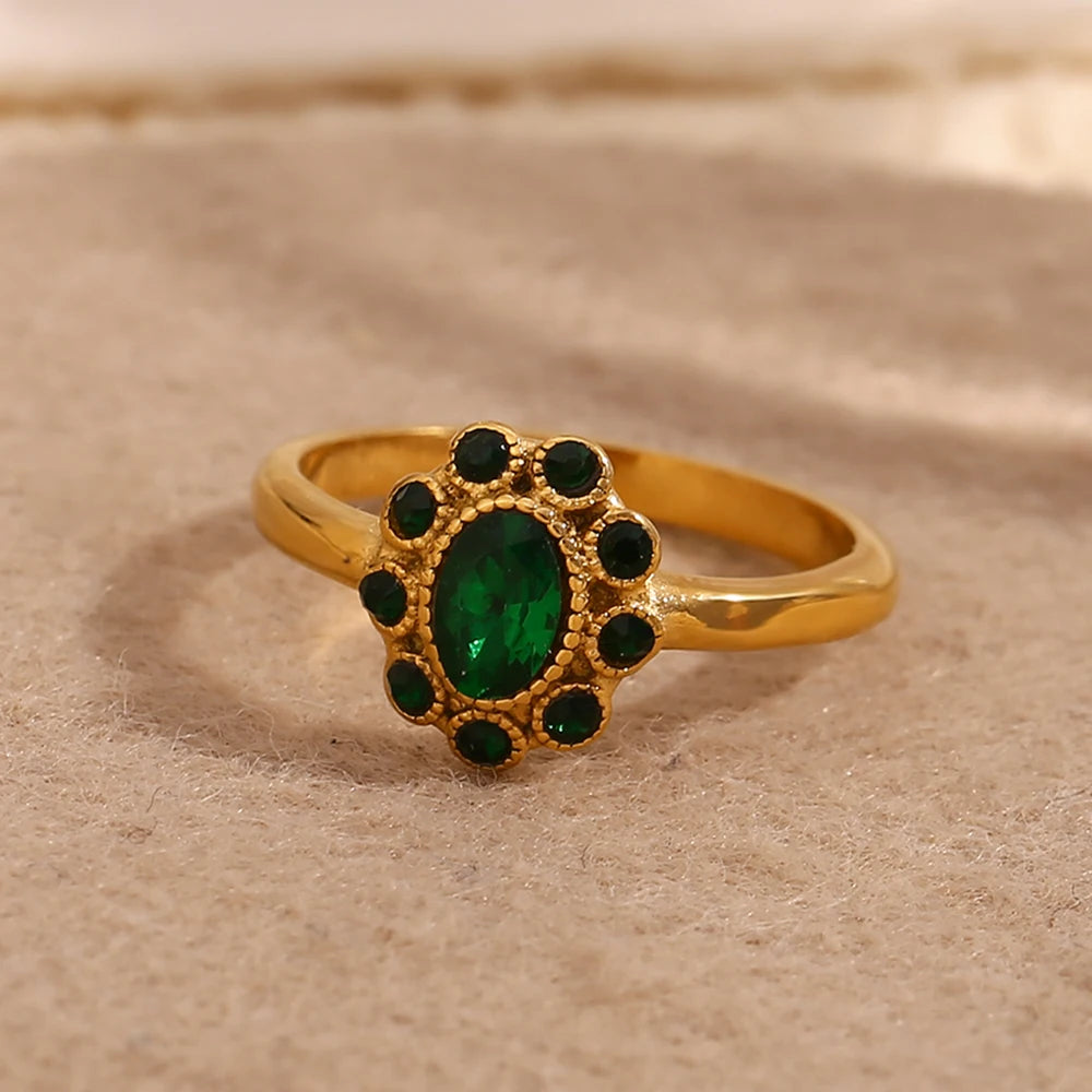 Gold ring with a green gemstone on a beige background