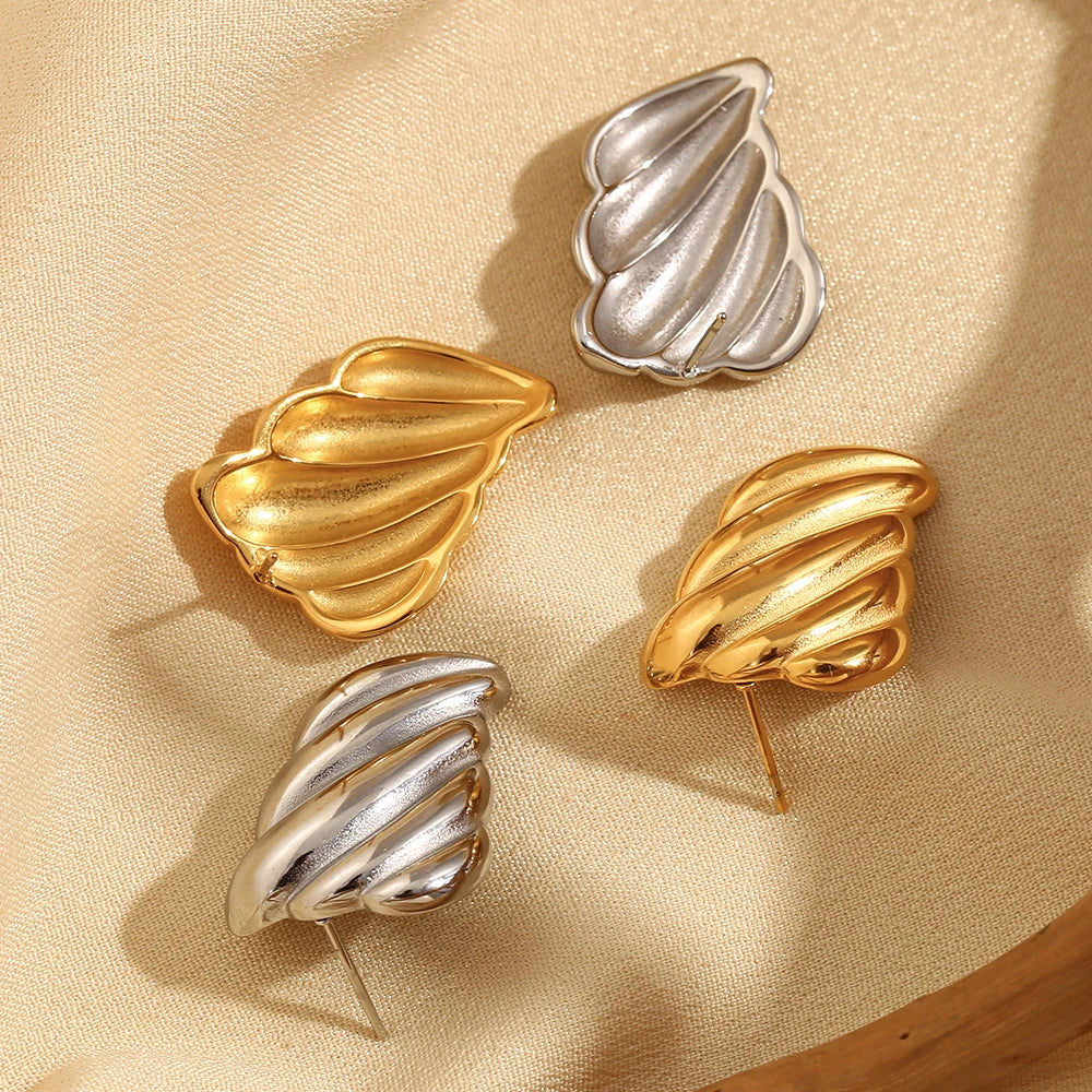 A pair of siver or 18K gold plated stainless steel earrings with a sculpted, wave-like design.