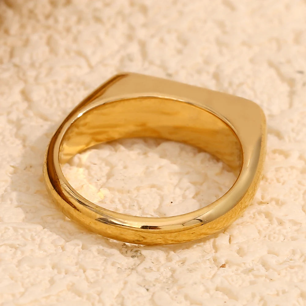 the backside of A gold-coated stainless steel ring with a white shell or black acrylic inset.