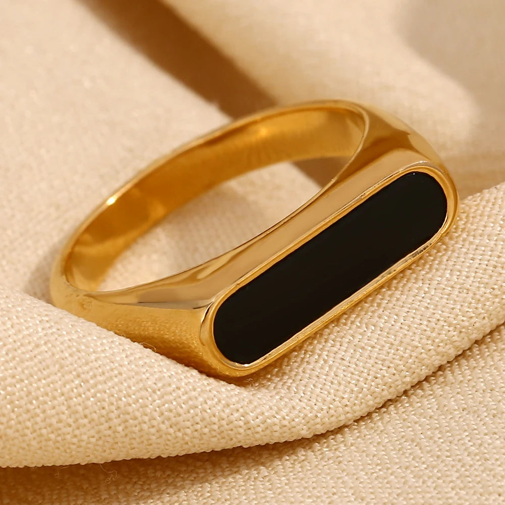 A gold-coated stainless steel ring with a black acrylic inset,displayed on fabric