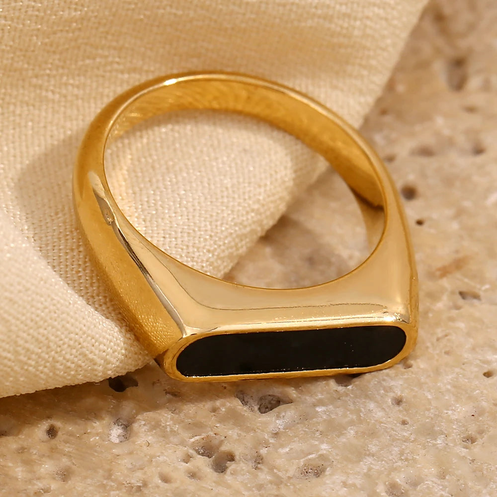 A gold-coated stainless steel ring with a black acrylic inset,