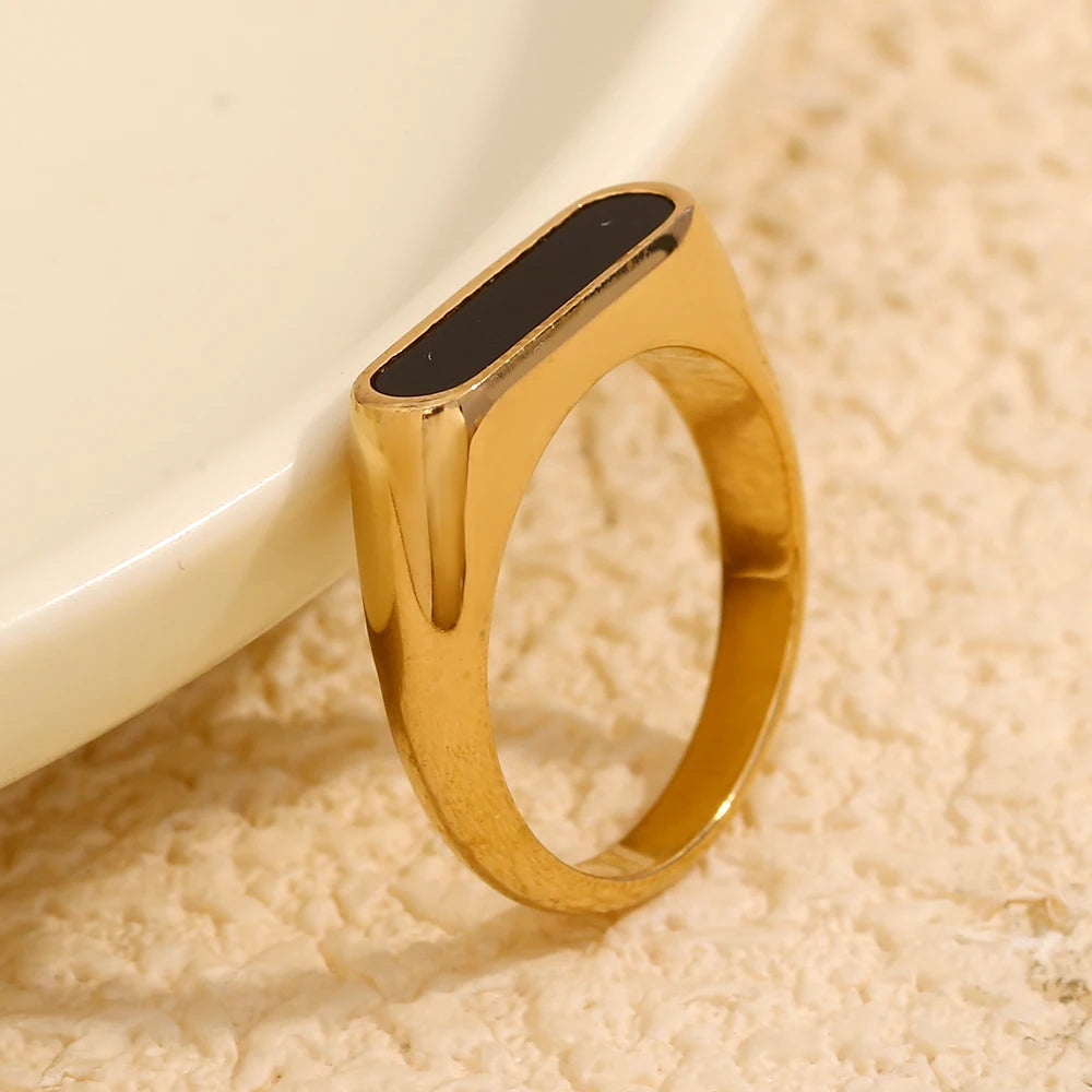 A gold-coated stainless steel ring with  black acrylic inset, on a model.
