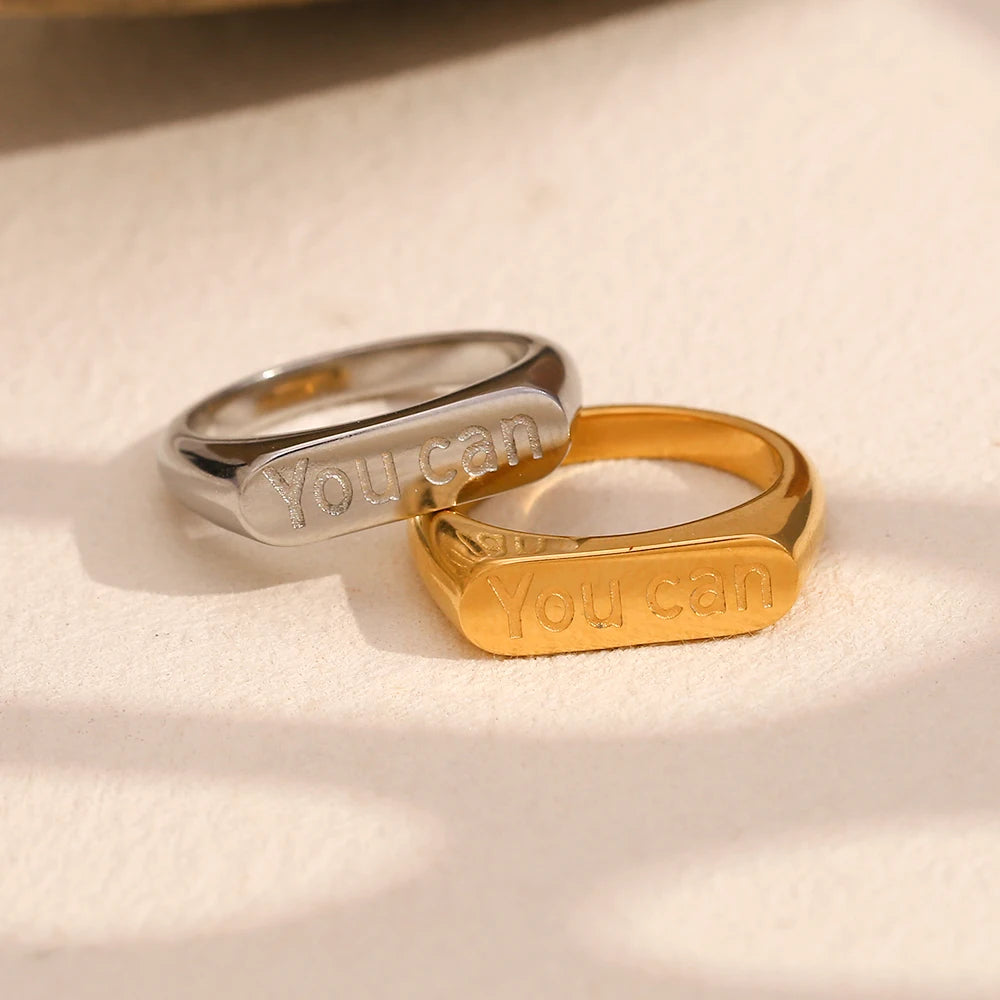 A stainless steel signet ring with the word 'you can' engraved on the top.